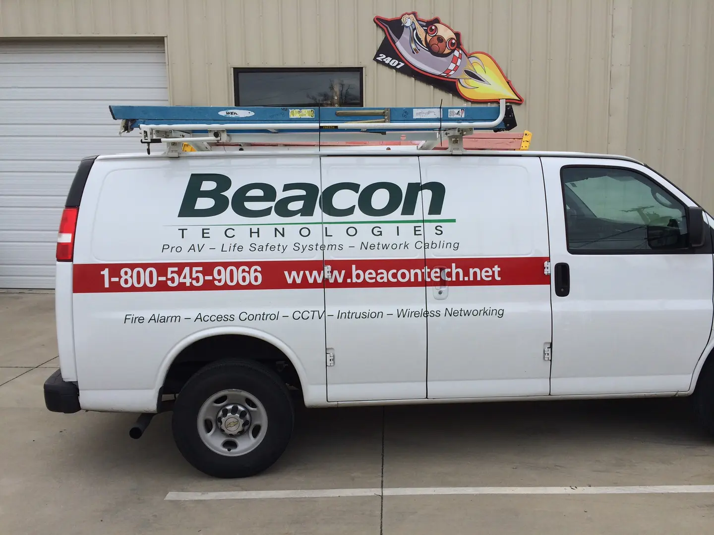 White service van with black lettering and a red stripe outside the Rocket Wraps shop