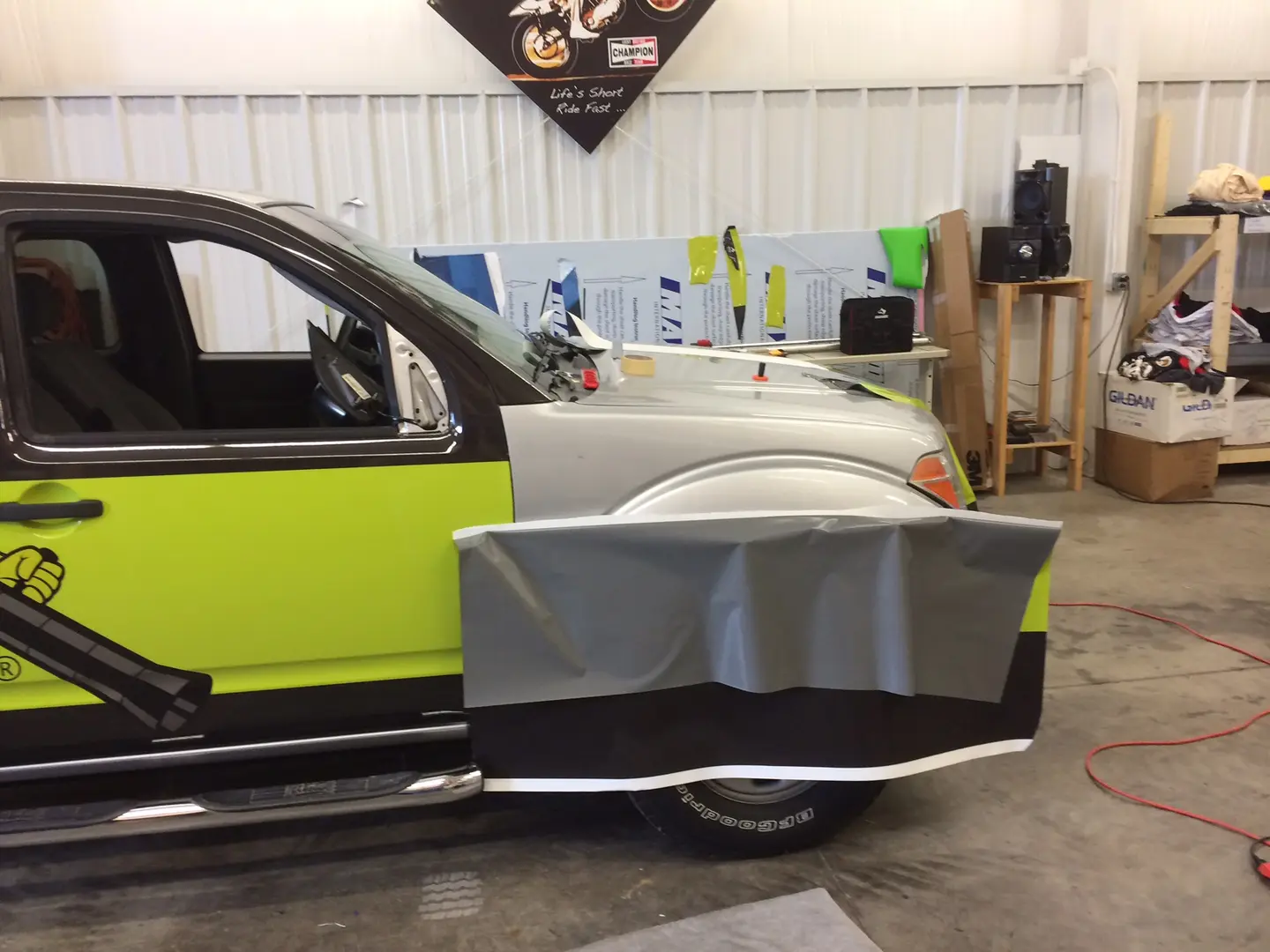 Pickup with bright yellow-green side graphics and a sheet of wrap material