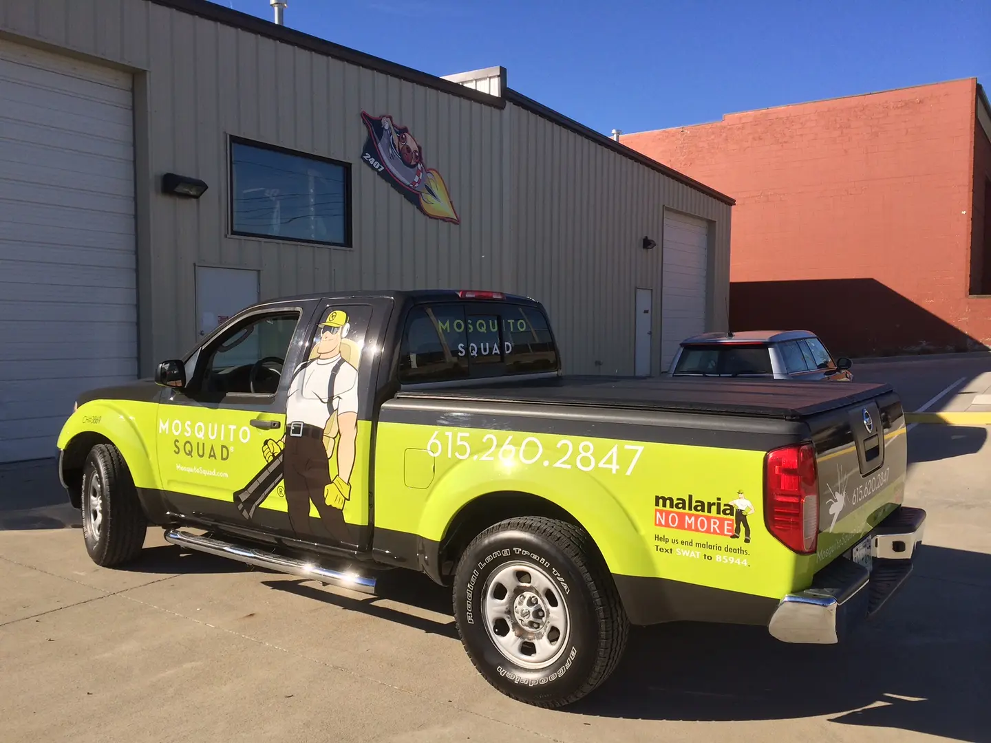 Pickup with bright yellow-green side graphics outside the shop