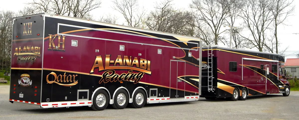 Large trailer with burgundy, gold and black graphics at an outdoor event