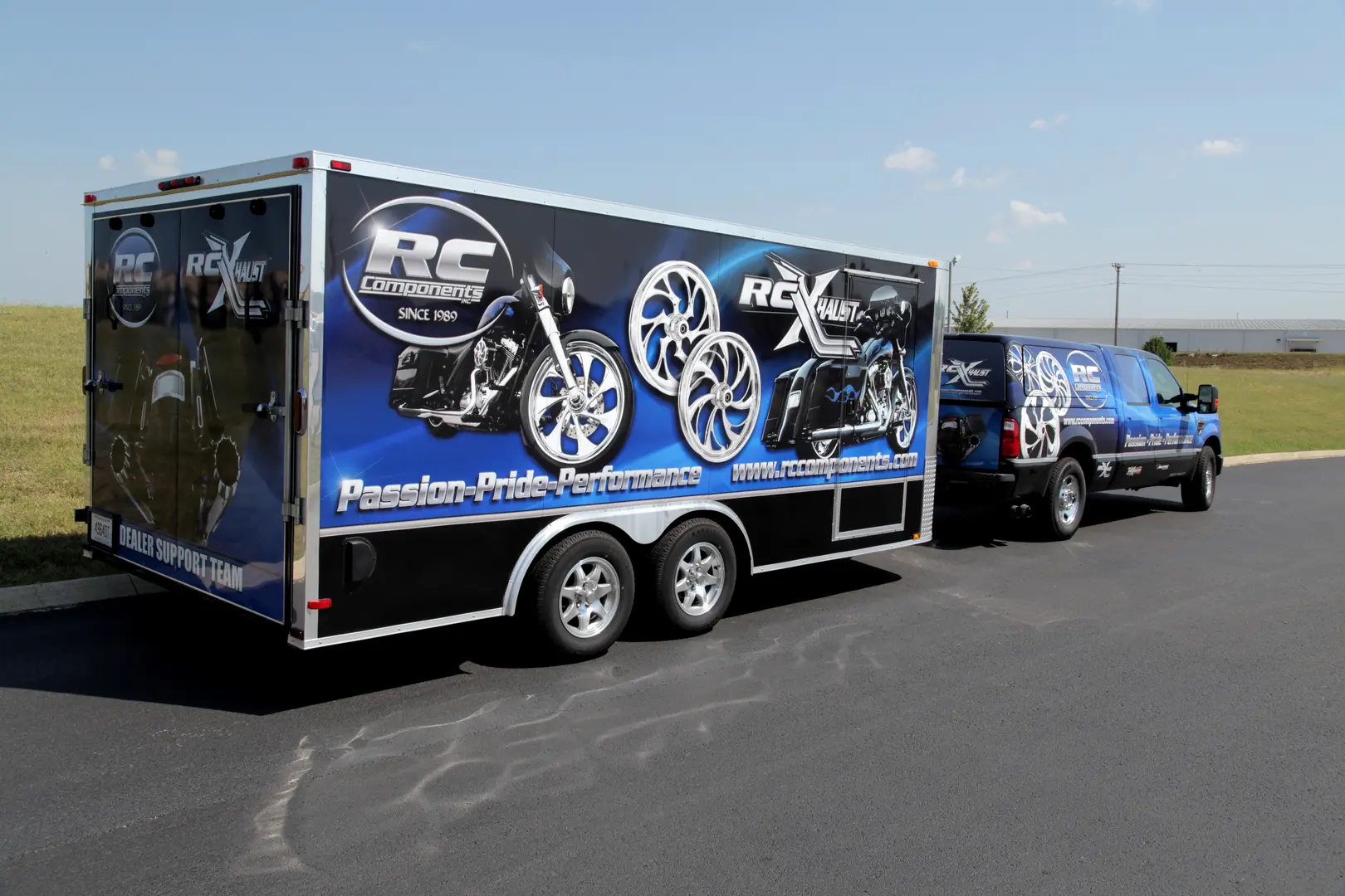 Blue enclosed trailer with white circular graphics beside a wrapped pickup