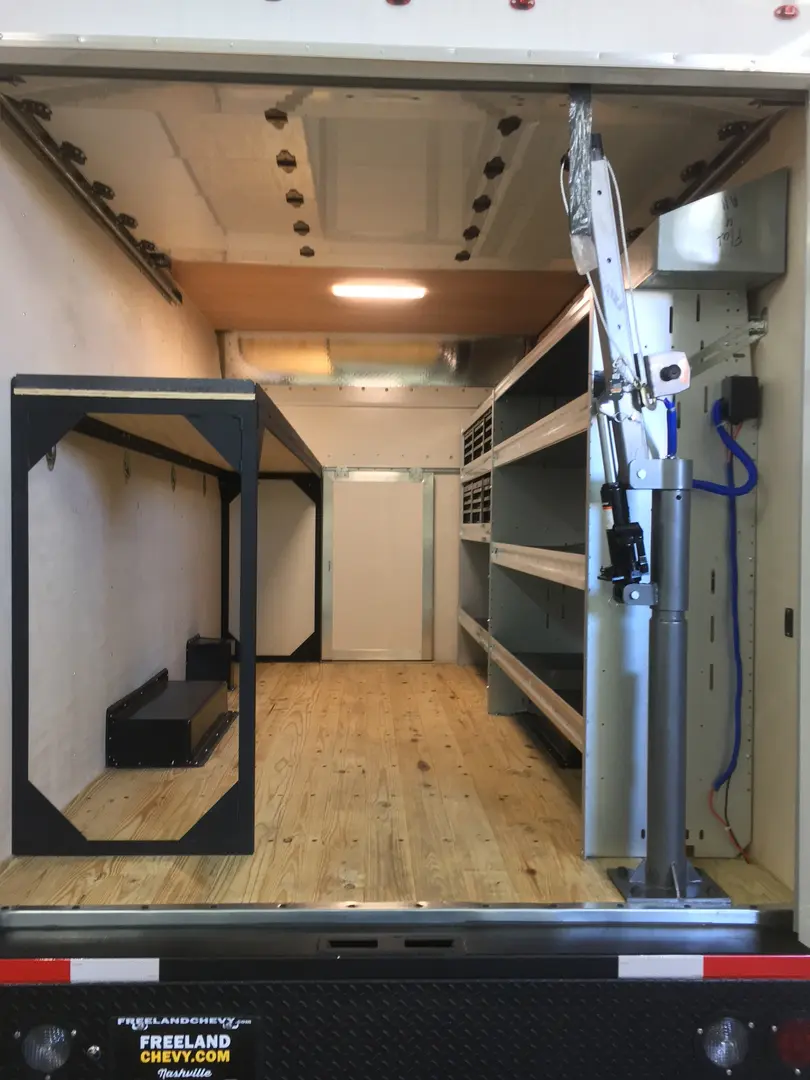 Open trailer interior with wood flooring, cabinets and storage racks