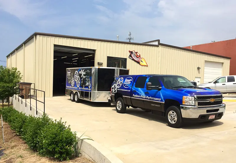 Blue pickup and enclosed trailer parked outside the wrap shop