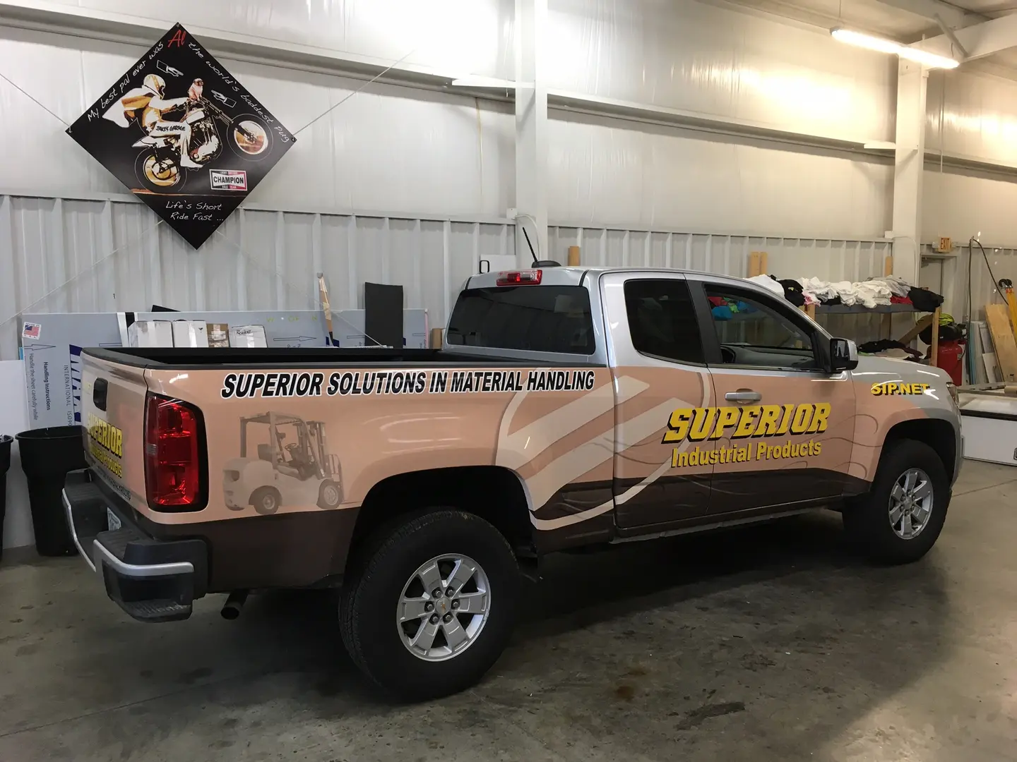 Gray pickup with illustrated industrial product graphics along its side