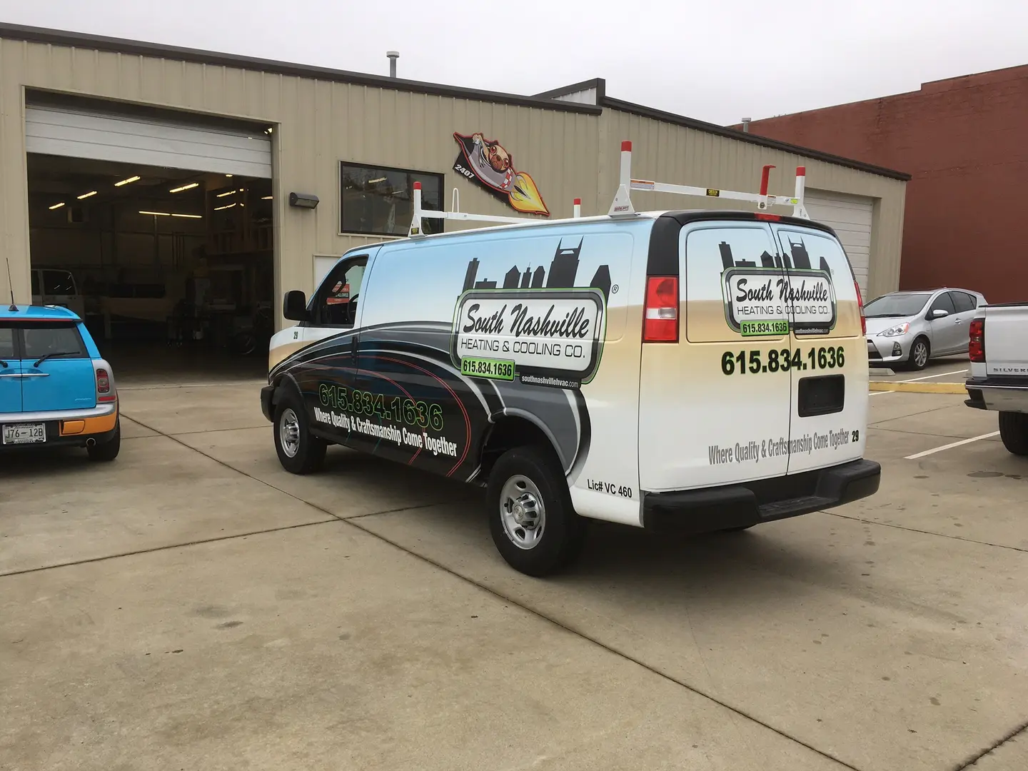 White work van with green and black business graphics outside the shop