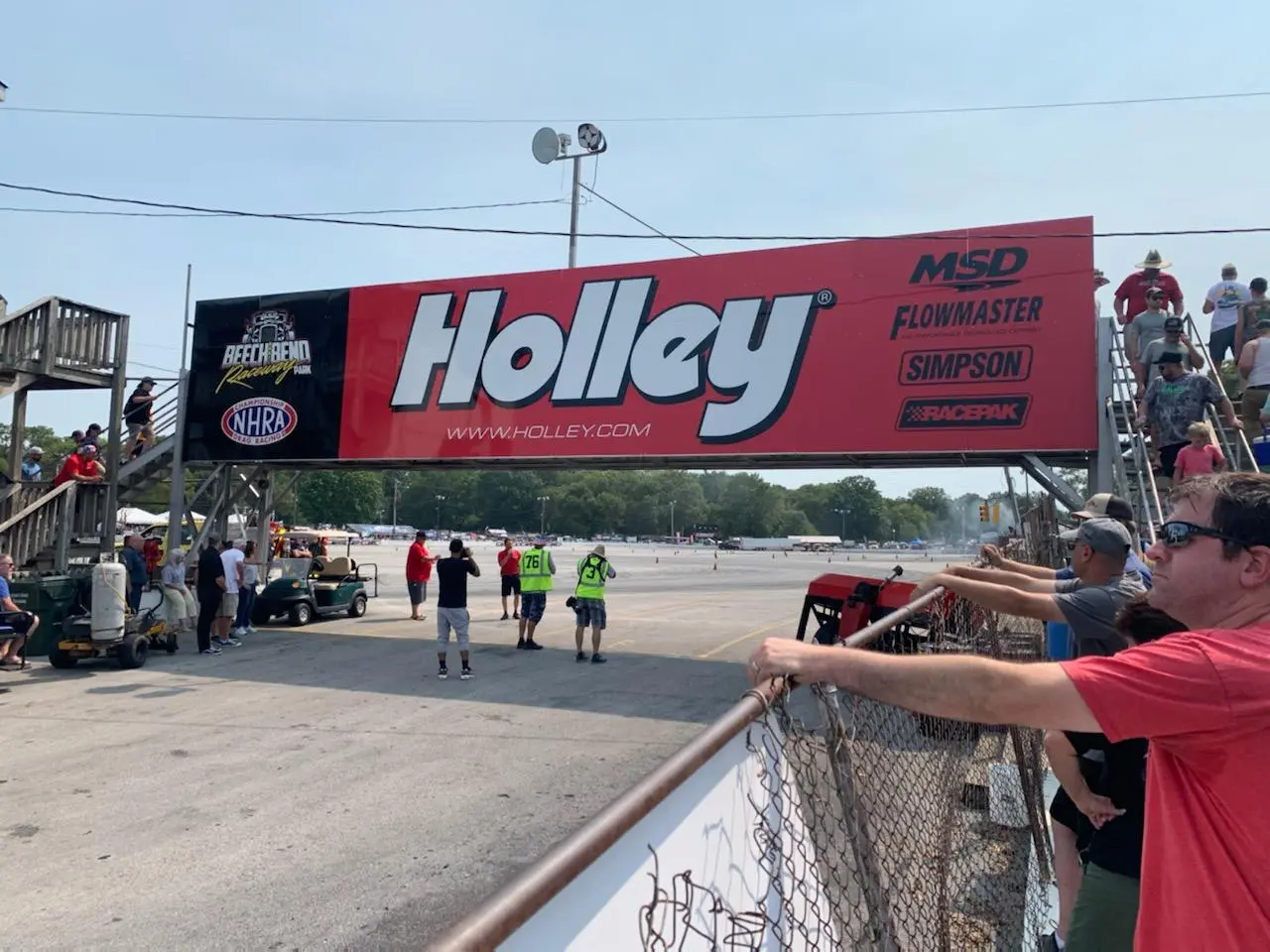 Large red event sign above an outdoor motorsport display