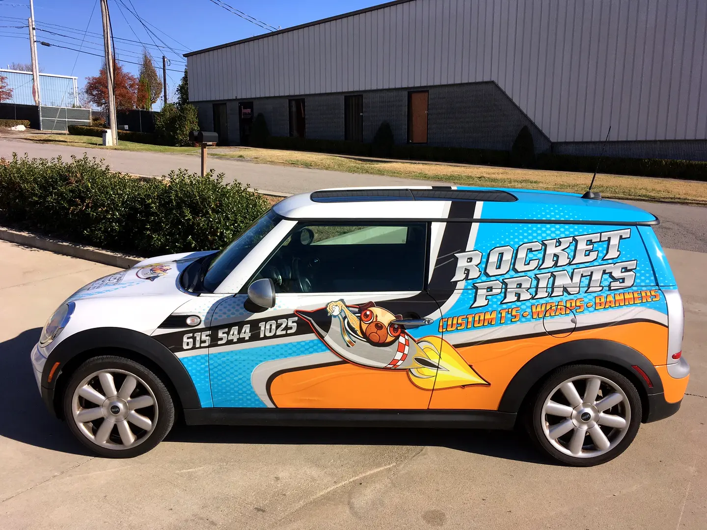White van with orange and blue graphics parked outside the shop