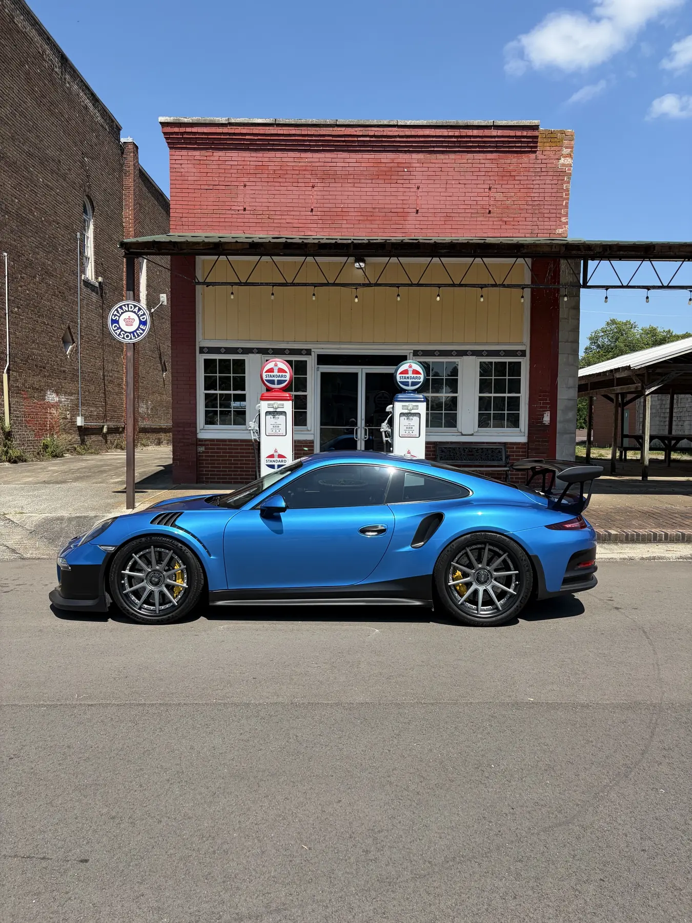 Blue coupe parked outside a brick building