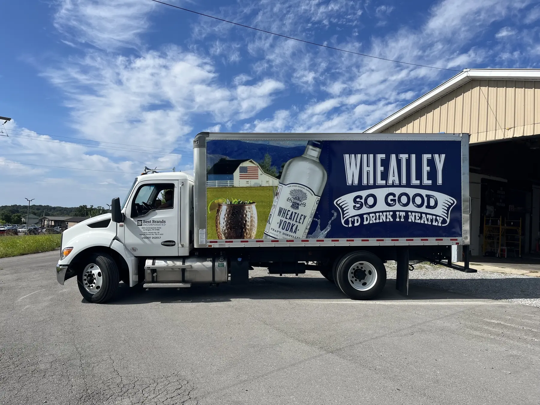White truck with a large dark blue side panel and beverage graphics