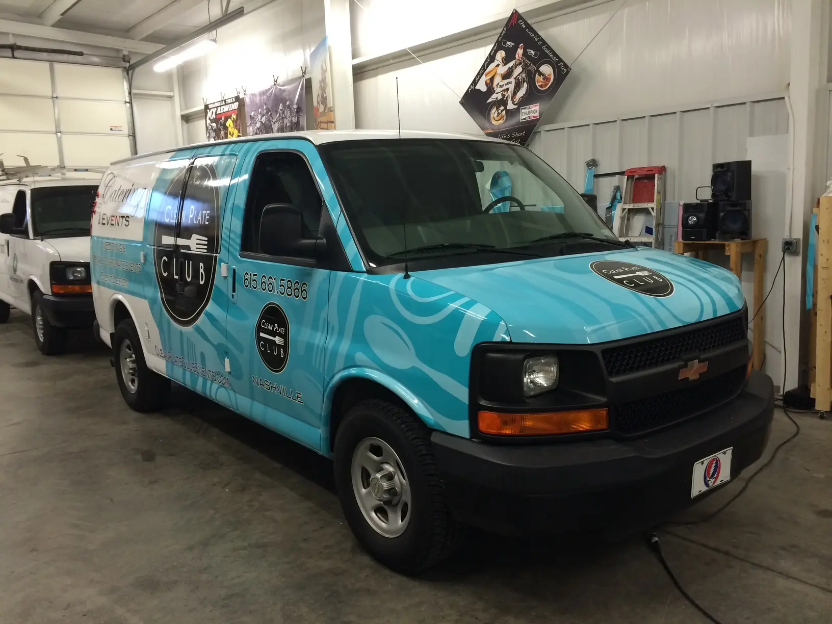 Turquoise van with catering graphics inside the wrap shop