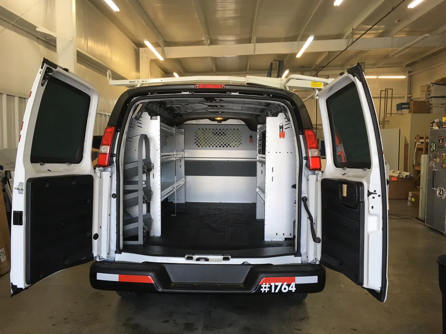 White work van with rear doors open to show shelving and storage