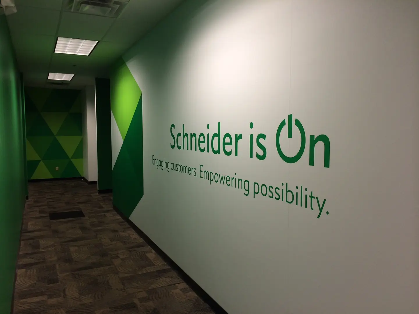 Green geometric wall graphics and lettering in an office corridor