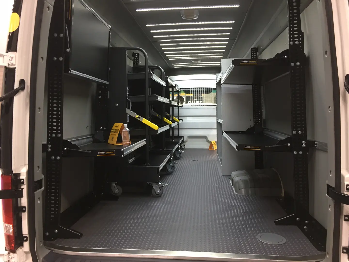 Cargo van interior with black storage units and overhead lighting